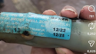 Close-up of a tear smoke shell casing showing a printed label with manufacture and expiry-adjacent dates
